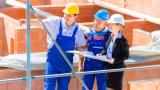 Architekten, Planer und Handwerker besichtigen eine Baustelle