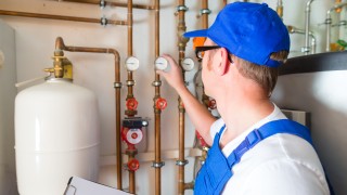 Installateur an Gasheizung Gasinstallateur kontrolliert eine Heizungsanlage im Keller